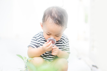 Asian baby boy Looking At green leaf Through Magnifying Glass at home on white Background.Concept for research global warming, global network,SEO search engine and Kid Education of ecology.