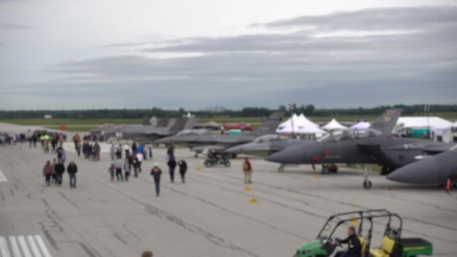 Row Of Jet Fighter Planes On Aircraft Strip With People Walking By During Outdoor Airshow Aerial View