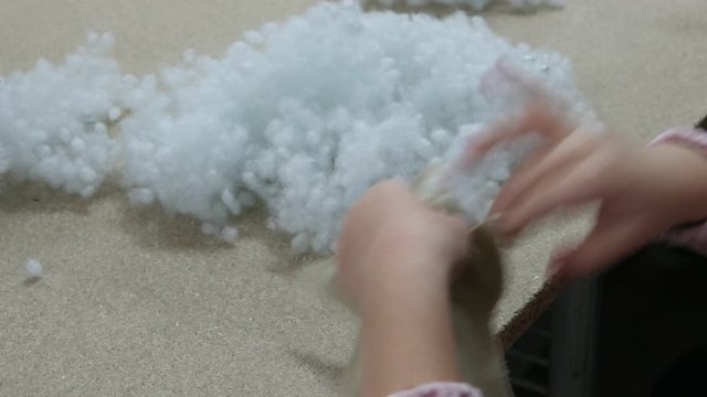 Girl fills handmade textile Christmas decoration with white fluffy stuffing for soft toys