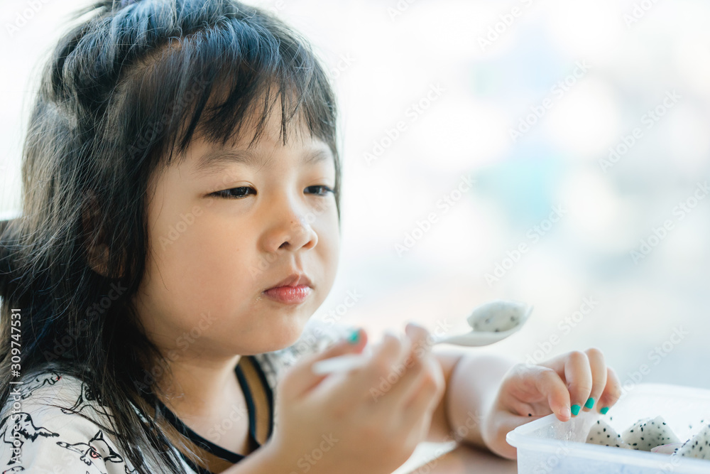 Wall mural Little asian girl don't want to eat dragon fruit she hate every fruits.bored face bored food.5 years old girl does not want to eat her healthy foods