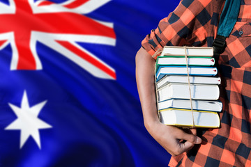 Australia national education concept. Close up of teenage student holding books under his arm with...