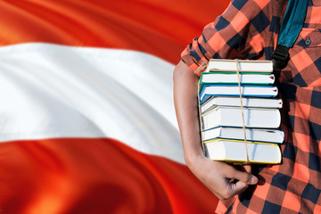 Austria national education concept. Close up of teenage student holding books under his arm with country flag background.