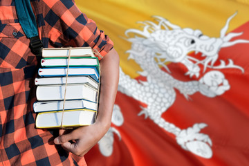 Bhutan national education concept. Close up of teenage student holding books under his arm with...