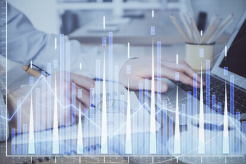 Multi exposure of stock market graph with man working on laptop on background. Concept of financial analysis.