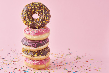 Stack of colorful donuts decorated on a pink background