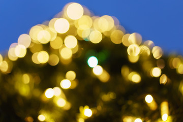 Photography of New Year lights on the fir with defocused background in night. Christmas mood, festive atmosphere. Suitable as template and background for postcards, greeting cards.
