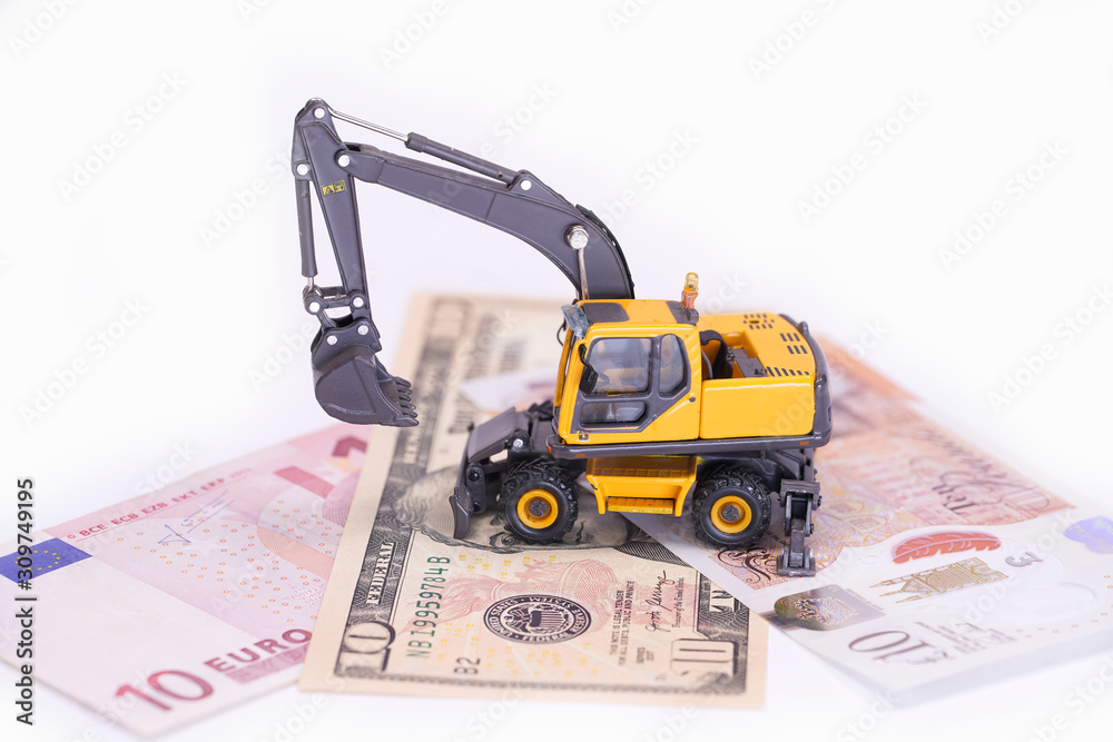 Wall mural yellow miniature excavator. the car is located on a dollar bill, euro and pounds