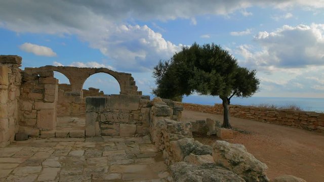 The ruins of the ancient walls in the archaeological park near Paphos against the backdrop of a cloudy stormy sky. Island of Cyprus.