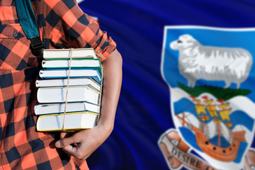 Falkland Islands national education concept. Close up of teenage student holding books under his arm with country flag background.