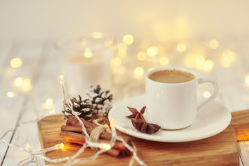 Cup of coffee with a garland lights and decoration on table. Cozy home concept
