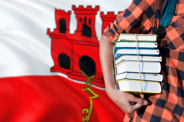 Gibraltar national education concept. Close up of teenage student holding books under his arm with country flag background.