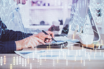 Forex graph with businessman working on computer in office on background. Concept of hardworking. Closeup. Multi exposure.