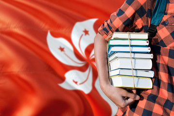 Hong Kong national education concept. Close up of teenage student holding books under his arm with country flag background.