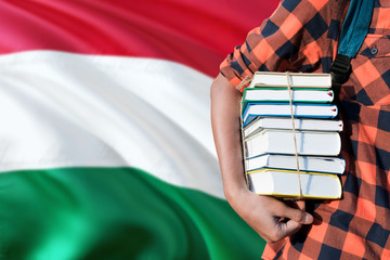 Hungary national education concept. Close up of teenage student holding books under his arm with country flag background.