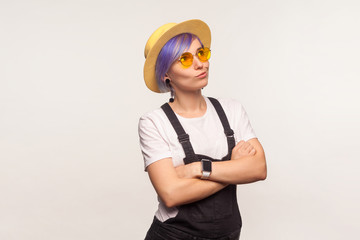 Let me think. Portrait of pensive glamour hipster girl with violet hair in sunglasses and hat crossing hands and pondering idea, having doubts, thoughtful expression. white background, studio shot