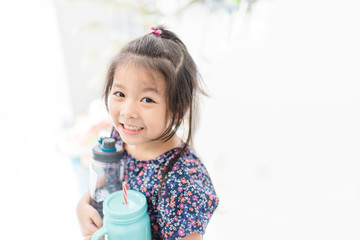 Little asian girl holding reuse bottle for drink.Reusable products, plastic free, eco living and Zero waste concept.Ecology go green,Save the earth concept.