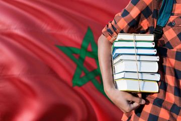 Morocco national education concept. Close up of teenage student holding books under his arm with country flag background.