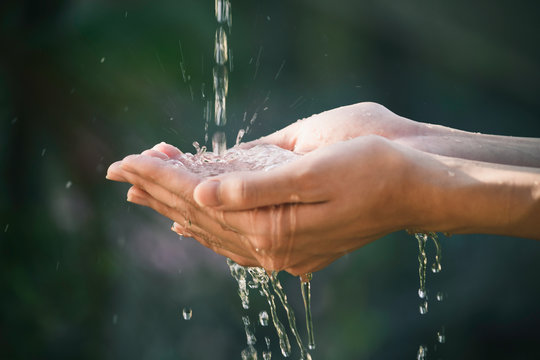 closeup water flow to hand of women for nature concept on the garden background.