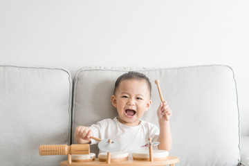 Little baby drummer boy playing and hitting the drum set at home.Asian boy playing and singing...