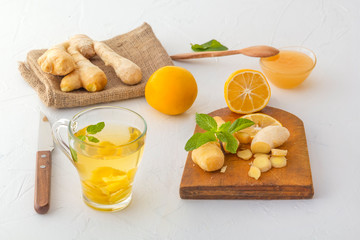Obraz na płótnie Canvas Ginger tea with lemon, honey and mint on a white wooden table