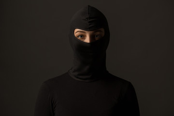Unknown woman in a black mask on a gray background