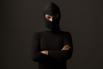 Unknown woman in a black mask on a gray background