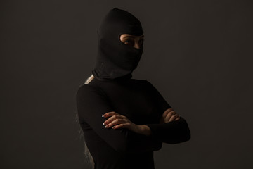 Unknown woman in a black mask on a gray background