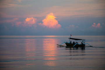 Balinese boat with tourists during sunset colors over the calm sea in Lovina