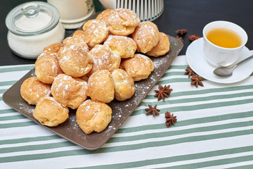 profiteroles, custard cake on a table with tea