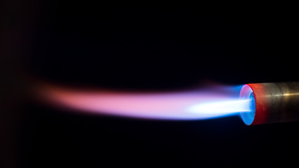 Side view, a nozzle with a jet of blue flame