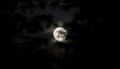 Full moon in dark sky with clouds