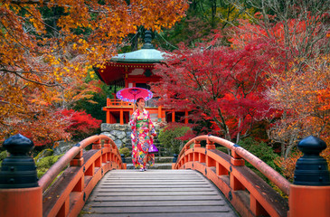 Fototapeta premium Japonka w tradycyjnym stroju kimono spacer w czerwonym moście w świątyni Daigoji
