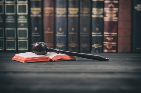 Judge Gavel and law book on a black wooden background, law library concept.
