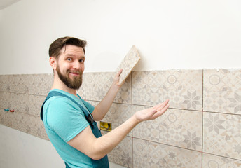 Male worker showing how good work he did installing ceramic tiles 