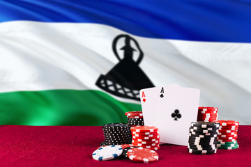 Lesotho casino theme. Aces in poker game, cards and chips on red table with national flag background. Gambling and betting.