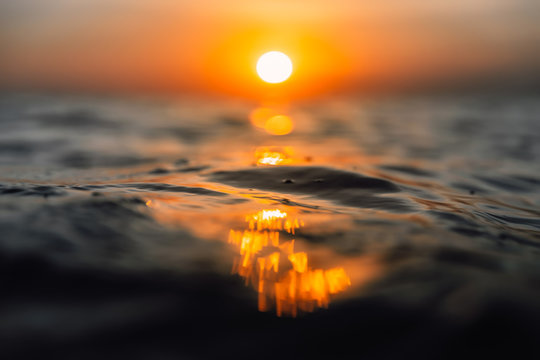 Sunset and waves in ocean. Warmy water texture with bokeh