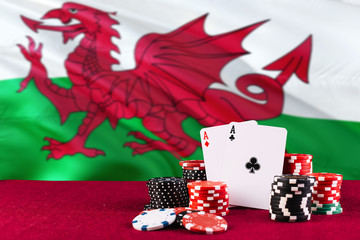 Wales casino theme. Aces in poker game, cards and chips on red table with national flag background. Gambling and betting.