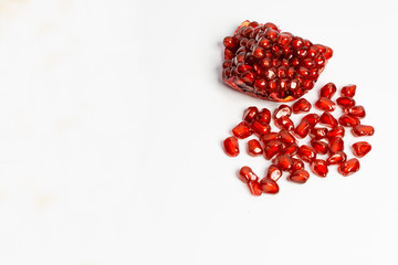 Spoon with ripe pomegranate seeds on a white isolated background.
