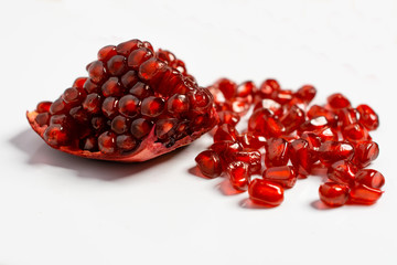 Spoon with ripe pomegranate seeds on a white isolated background.