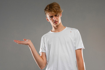 Young caucasian man in white t-shirt posing and gesticulating on camera isolated on grey background