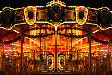 partial view of beautiful carousel with many light at night in theme park