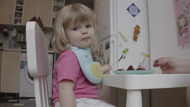 Little two years old blond blue-eyed girl having her dining, ungraded mavic2pro d-log 10-bit source