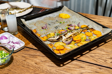 Baked Fish Bluefish with Sweet Potatoes on Oven Tray with Baking Paper Sheet / Lufer.