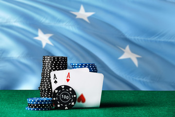Obraz premium Micronesia casino theme. Two ace in poker game, cards and black chips on green table with national flag background. Gambling and betting.