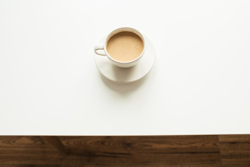 Cup of coffee with milk on white table. Top view minimal morning breakfast concept.