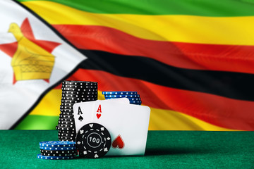 Zimbabwe casino theme. Two ace in poker game, cards and black chips on green table with national...