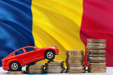 Chad savings concept. Money for new automobile, toy car and coin piles standing on national flag...