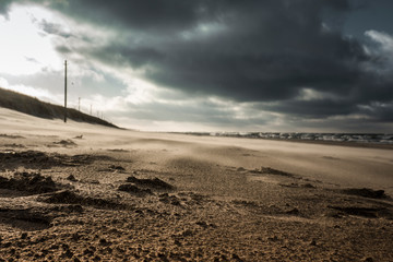 The wind raises the beach sand. A storm is approaching from the sea