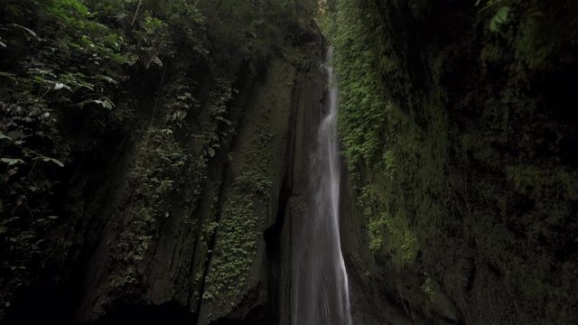 Beautiful Air Terjun Leke Leke waterfall located in Ubud at Bali surrounded by tropical forest natural background. The flow of hidden waterfall in the jungle surrounded by trees and rocks.