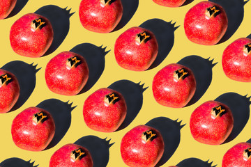 Pomegranate fruits in a row on a yellow background.